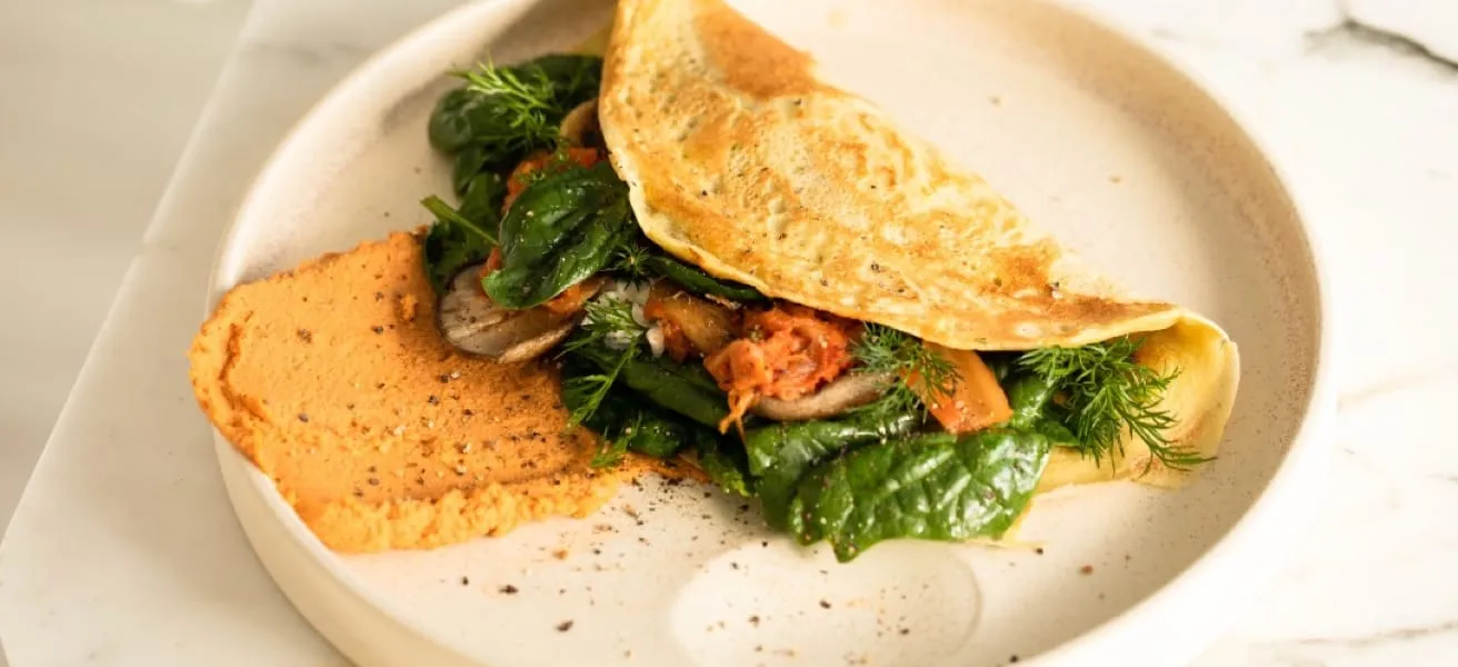 A delicious omelette served on a plate, accompanied by fresh vegetables